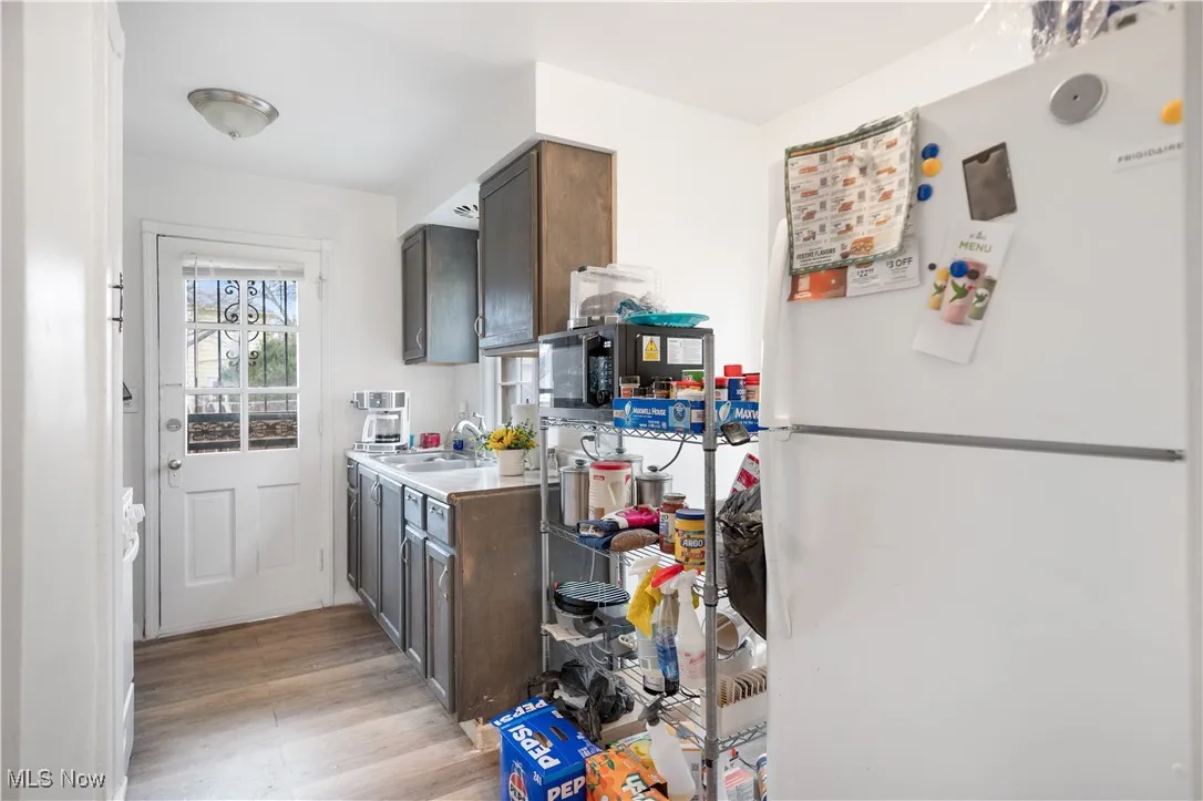 Kitchen featuring freestanding refrigerator, light countertops, light wood-style floors, and dark brown cabinets