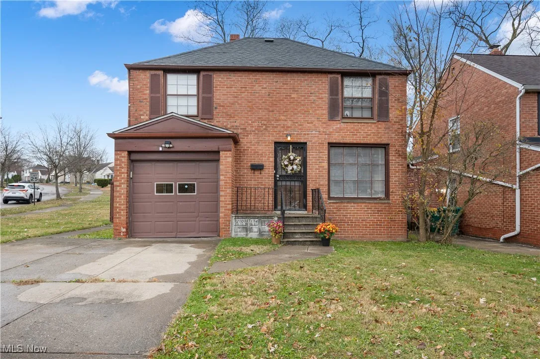 View of front facade with brick siding, a front yard, concrete driveway, and an attached garage