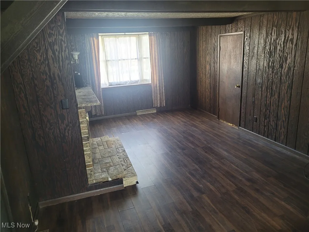 Unfurnished bedroom with dark wood finished floors and wooden walls