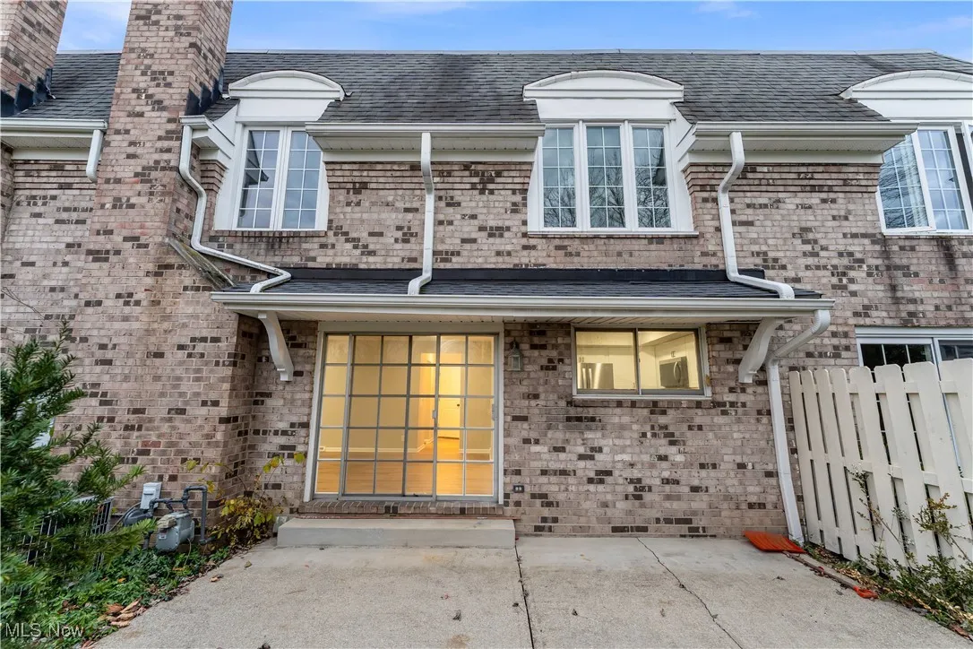 Doorway to property with a chimney, a shingled roof, and brick siding