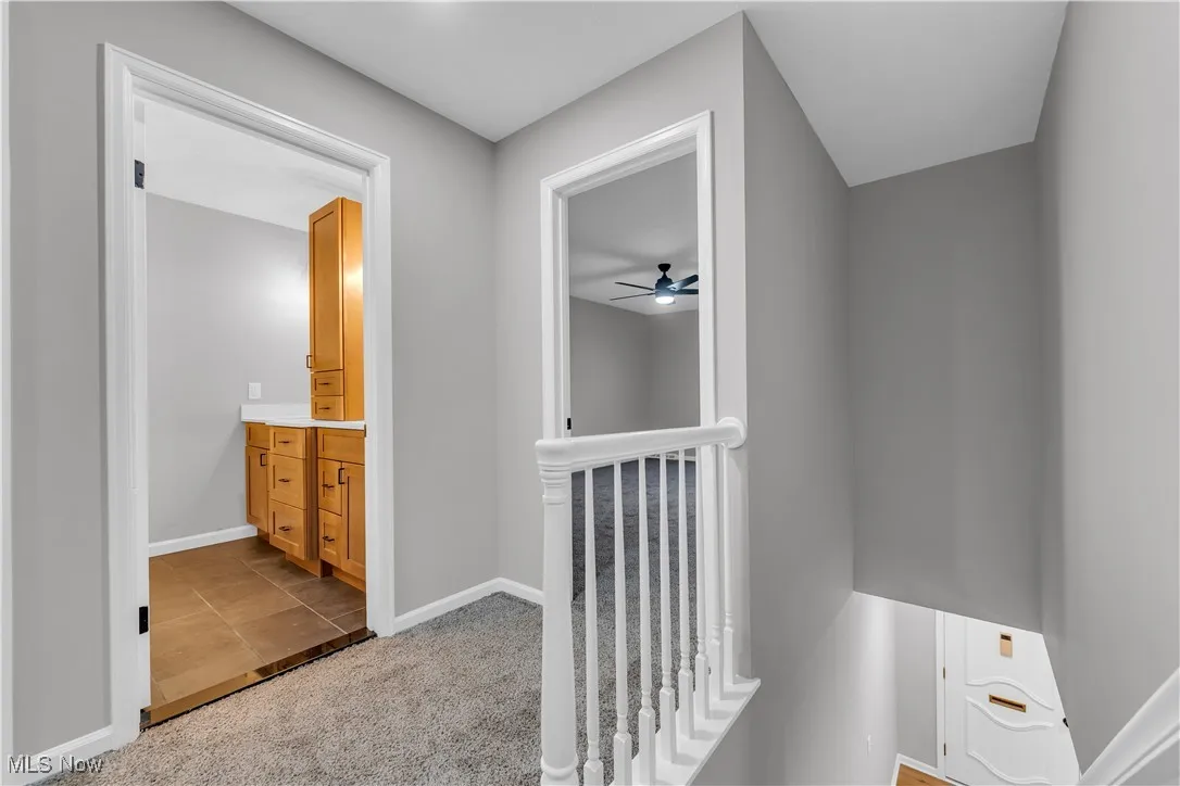 Hall featuring light colored carpet, an upstairs landing, and light tile patterned flooring