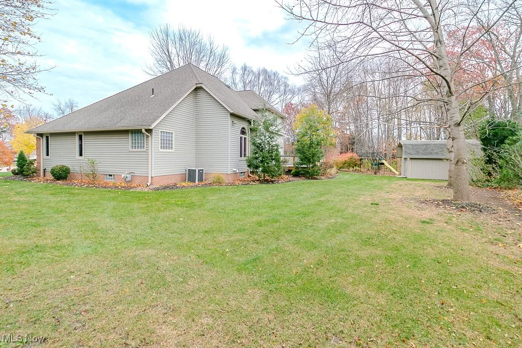 Back of property with a lawn, a wooden deck, and outbuilding