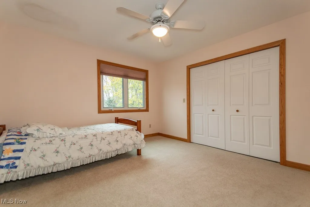Carpeted bedroom featuring a ceiling fan and a closet