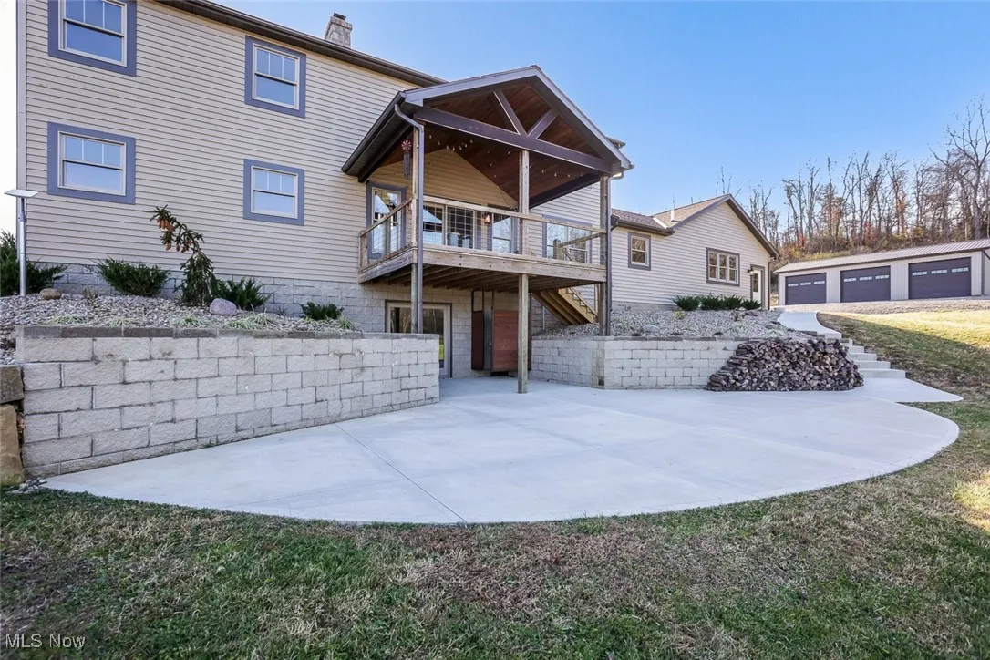 Back of house with an outdoor structure, a lawn, a chimney, and a garage
