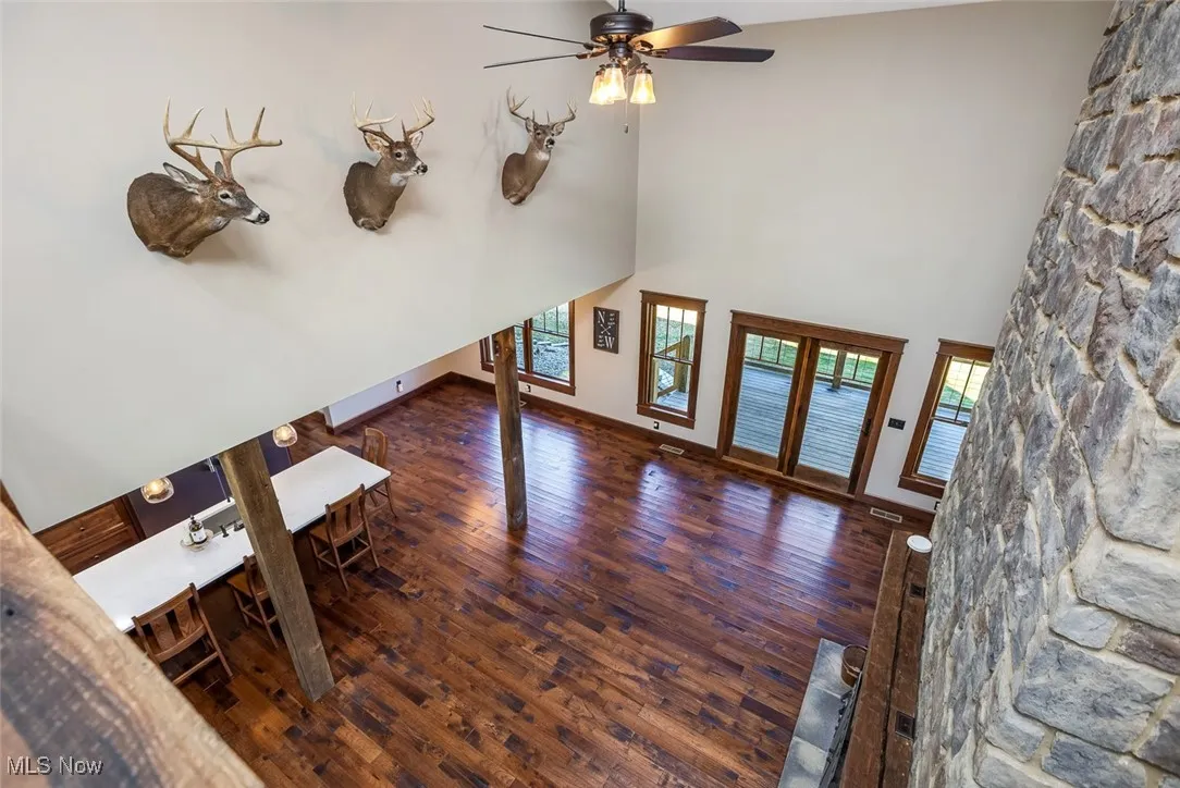 Unfurnished living room with dark wood-style flooring, a high ceiling, and ceiling fan