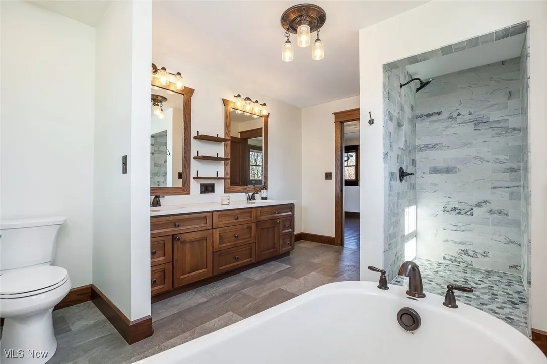 Bathroom featuring a soaking tub, a shower stall, and double vanity