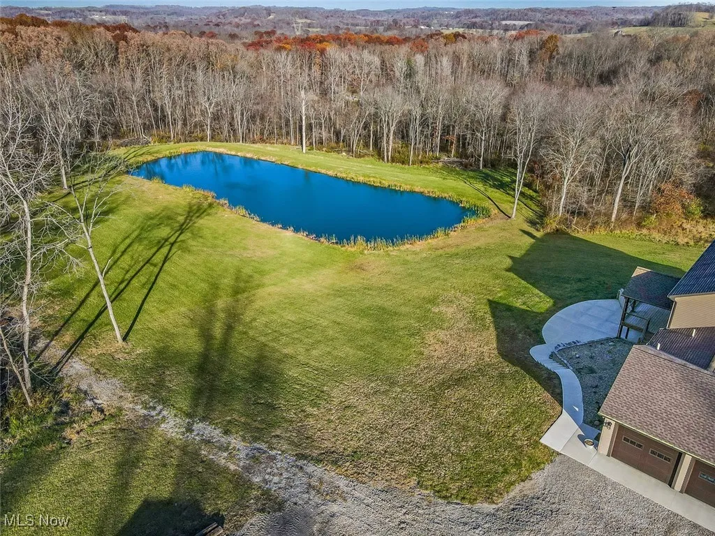 View of pool with a water view, a lawn, and a wooded view