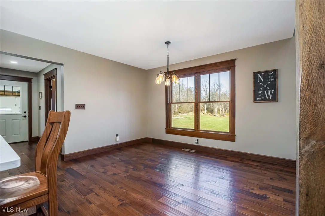 Unfurnished dining area with dark wood-style flooring and a chandelier