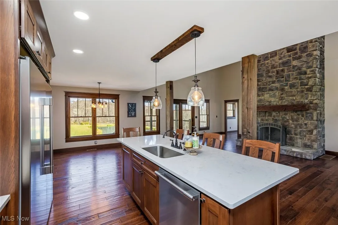 Kitchen with brown cabinets, stainless steel appliances, hanging light fixtures, and recessed lighting