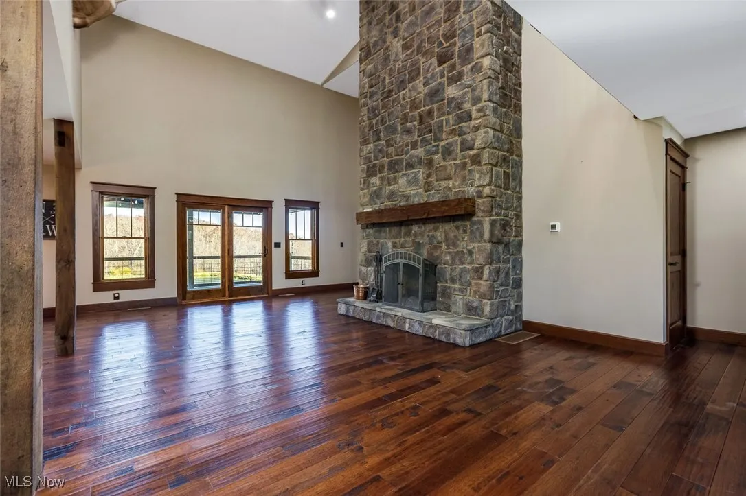 Unfurnished living room featuring dark wood finished floors, a fireplace, and a high ceiling