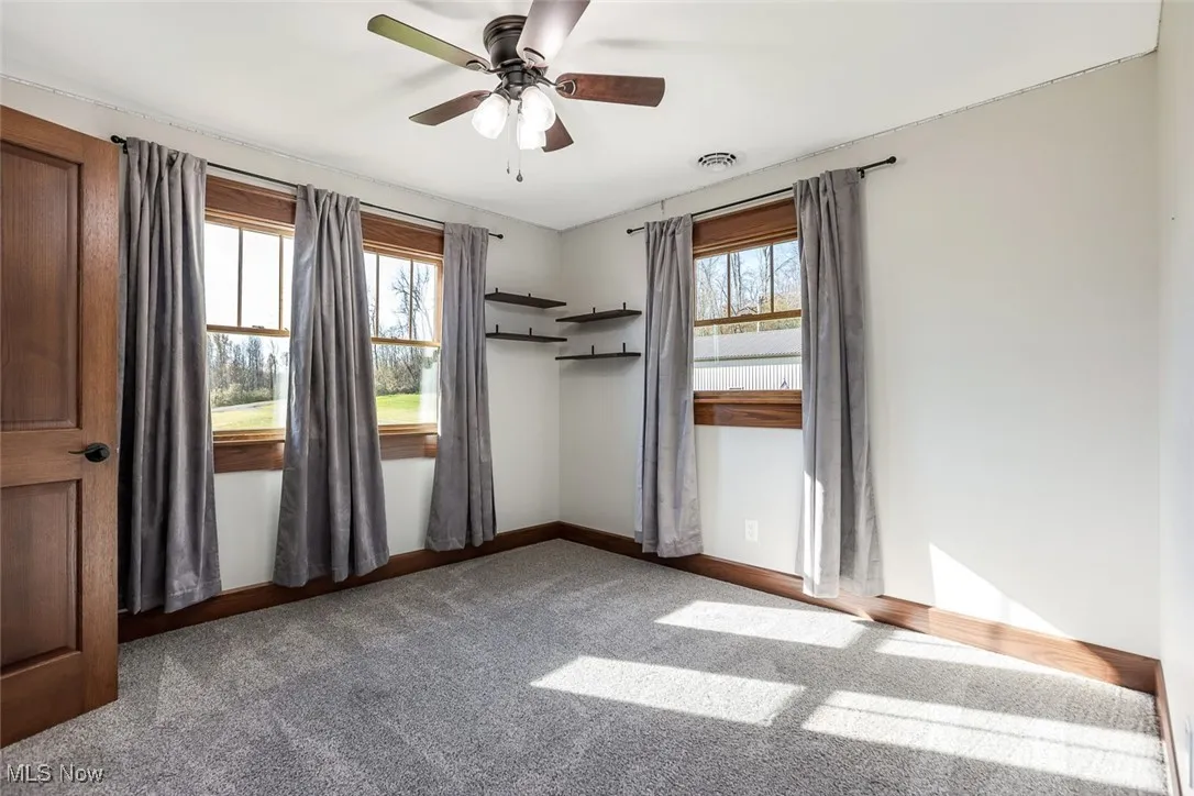 Empty room with carpet floors and ceiling fan