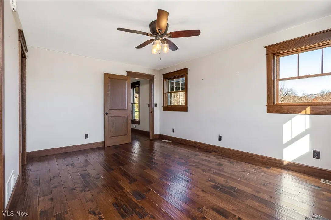 Empty room with dark wood-style flooring and a ceiling fan