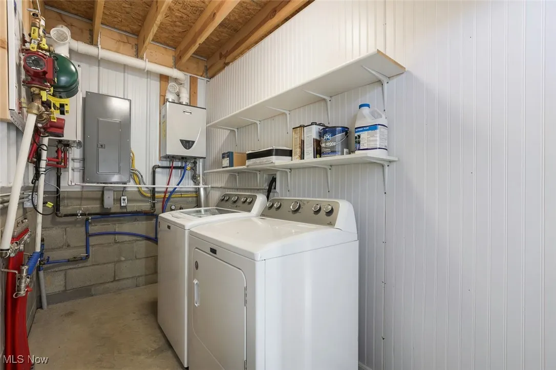 Laundry area with independent washer and dryer, electric panel, water heater, and unfinished concrete floors
