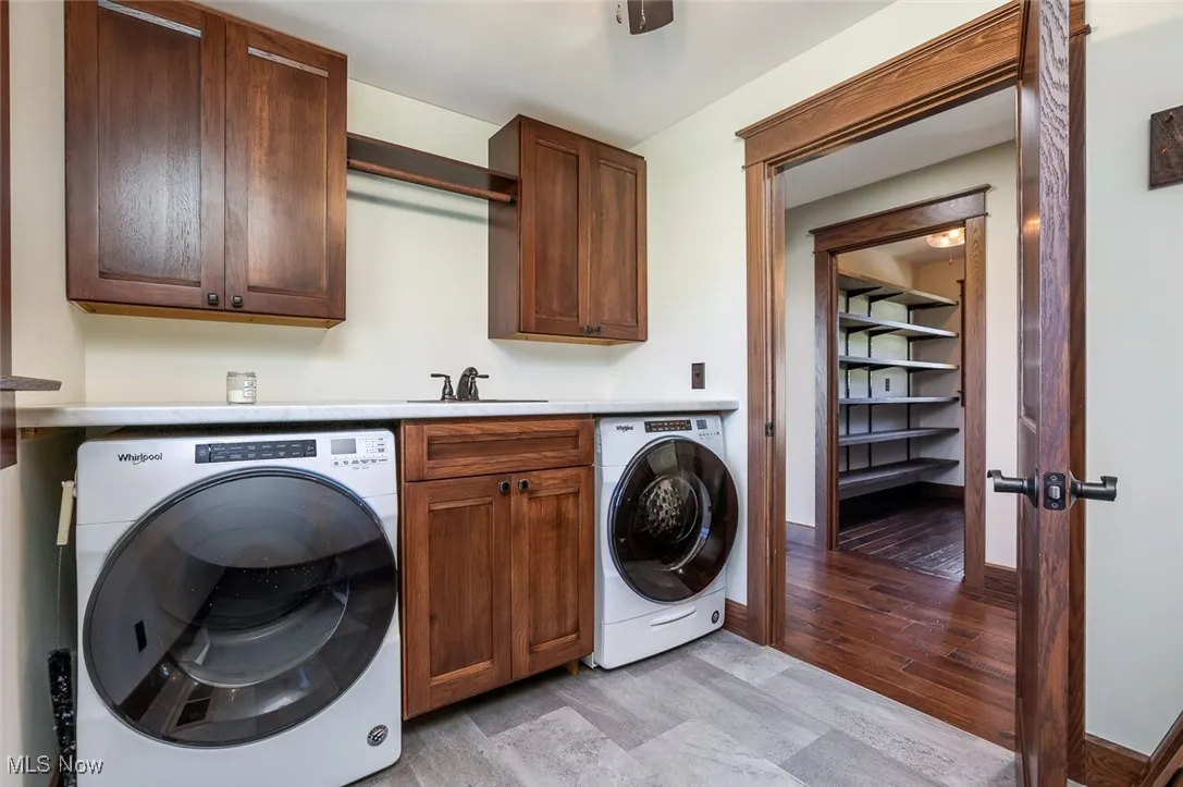Laundry area with light wood-style floors, cabinet space, and washing machine and dryer