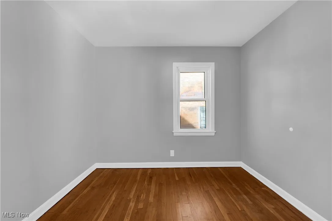 Empty room featuring dark wood-style flooring and baseboards