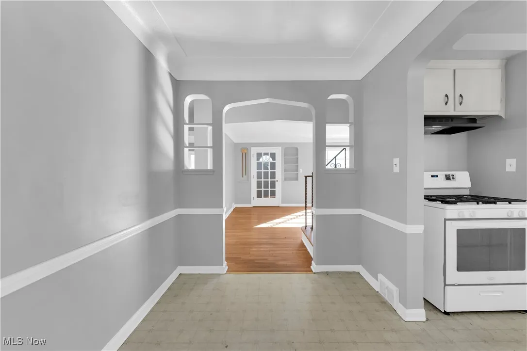 Kitchen with white gas range oven, arched walkways, healthy amount of natural light, and under cabinet range hood
