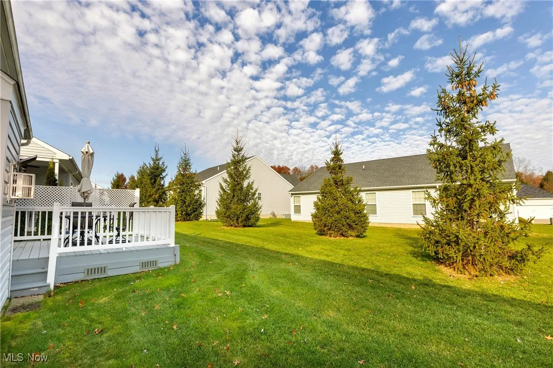 View of green lawn featuring a wooden deck