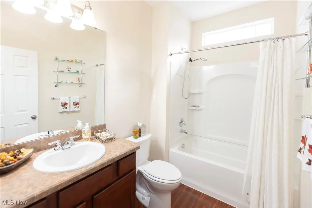 Bathroom featuring shower / bathtub combination with curtain, vanity, and dark wood-style flooring