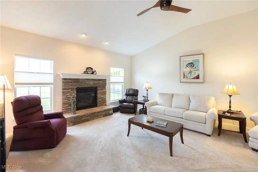 Living area featuring carpet, vaulted ceiling, a fireplace, a ceiling fan, and recessed lighting