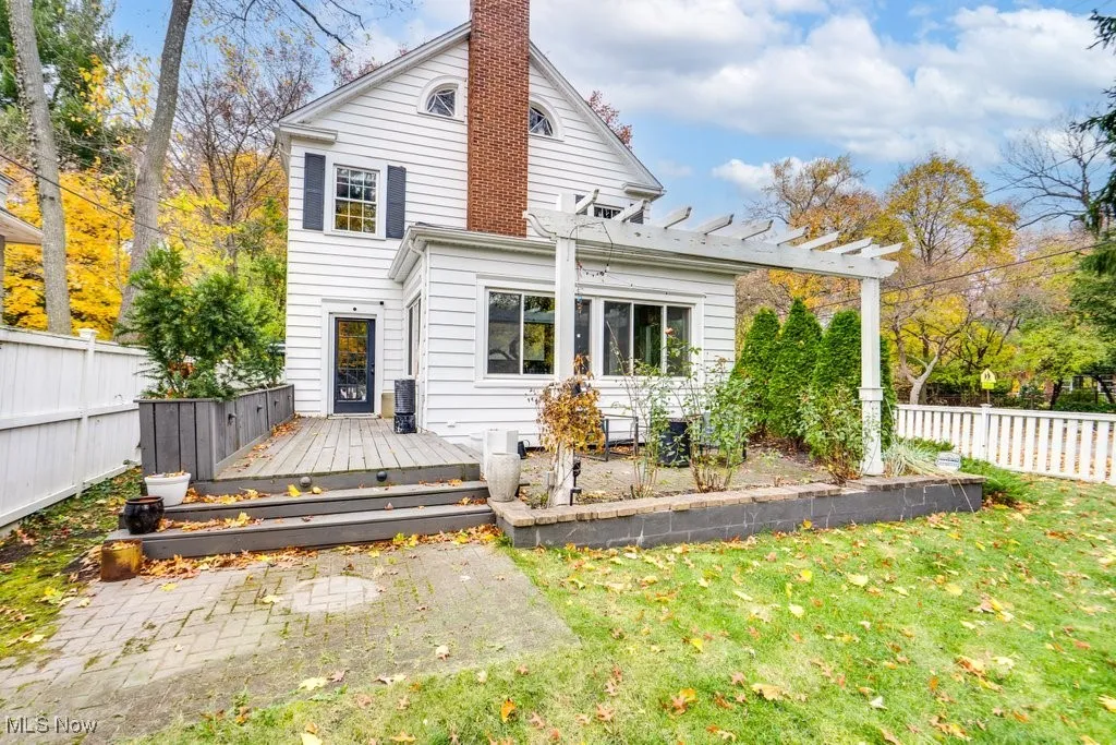 Rear view of house with a fenced backyard, a wooden deck, and a chimney