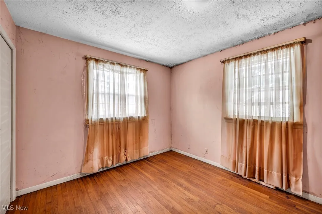 Spare room with hardwood / wood-style floors, plenty of natural light, and a textured ceiling