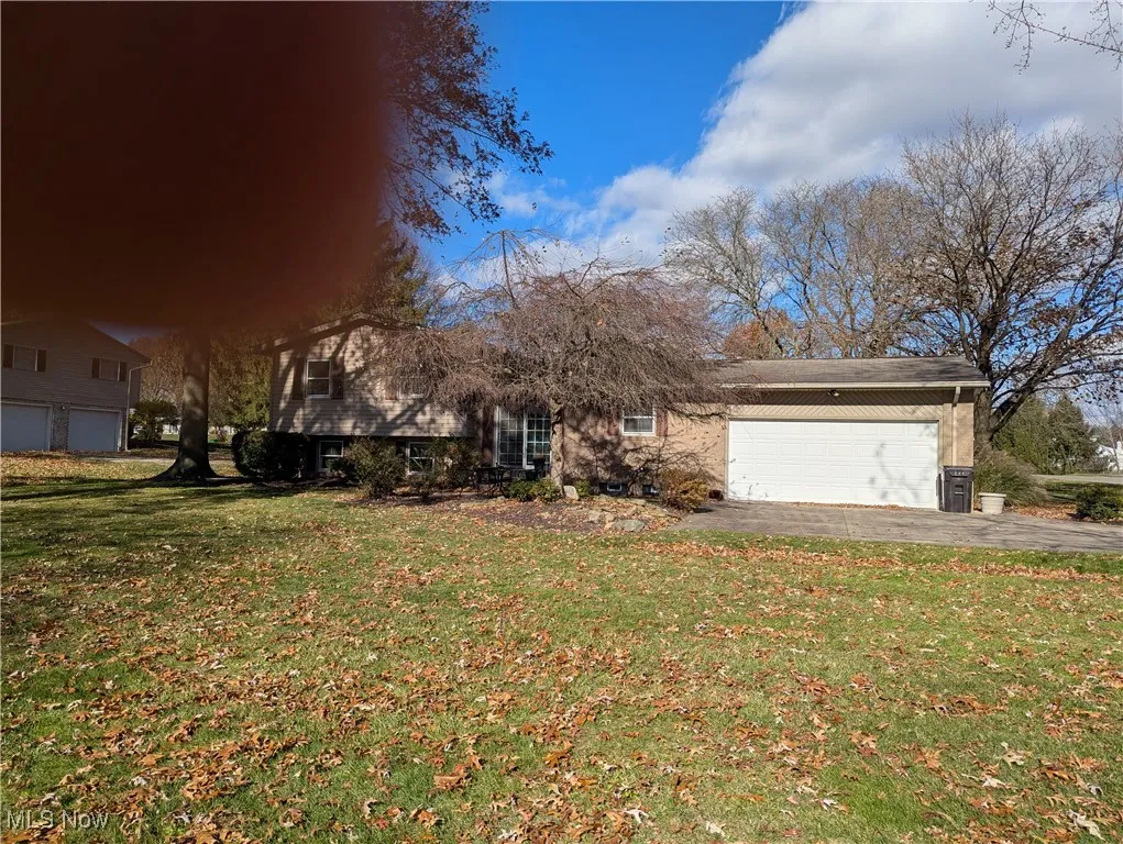 View of front of home featuring a front lawn, asphalt driveway, and an attached garage