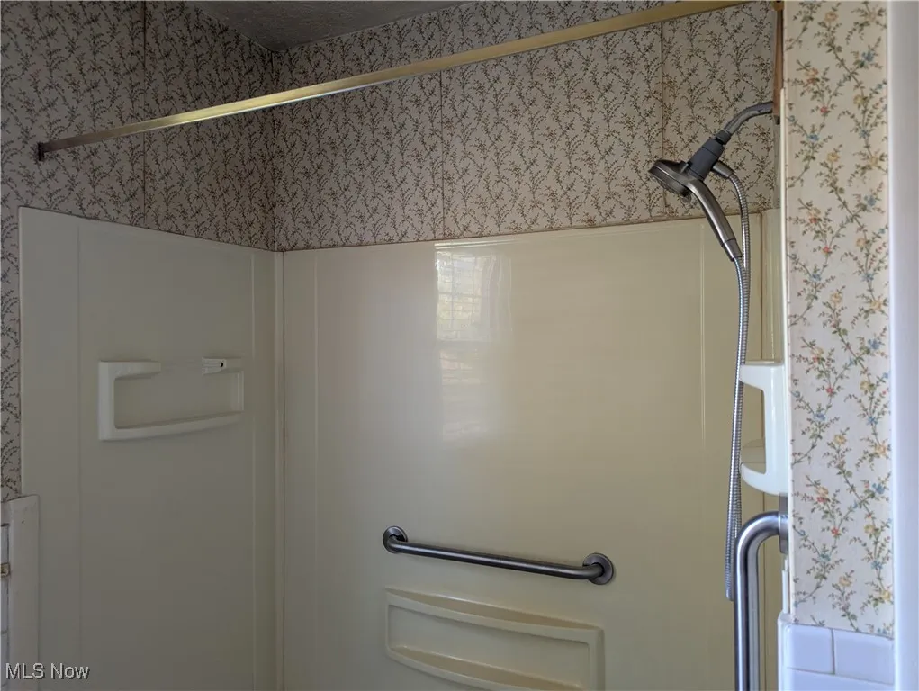 Bathroom view of wallpapered walls and an enclosed shower