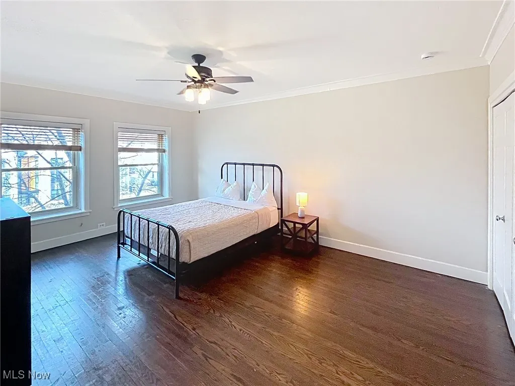Bedroom featuring crown molding, dark wood-type flooring, and a ceiling fan