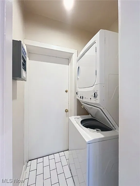 Laundry room with estacked washer and dryer and light tile patterned flooring