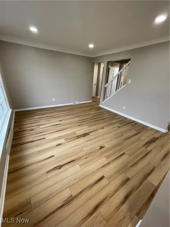 Empty room with recessed lighting, light wood-style flooring, and stairs