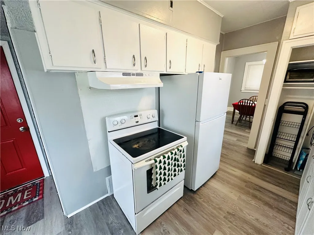 Kitchen with white range with electric cooktop, light wood-style floors, and white cabinetry