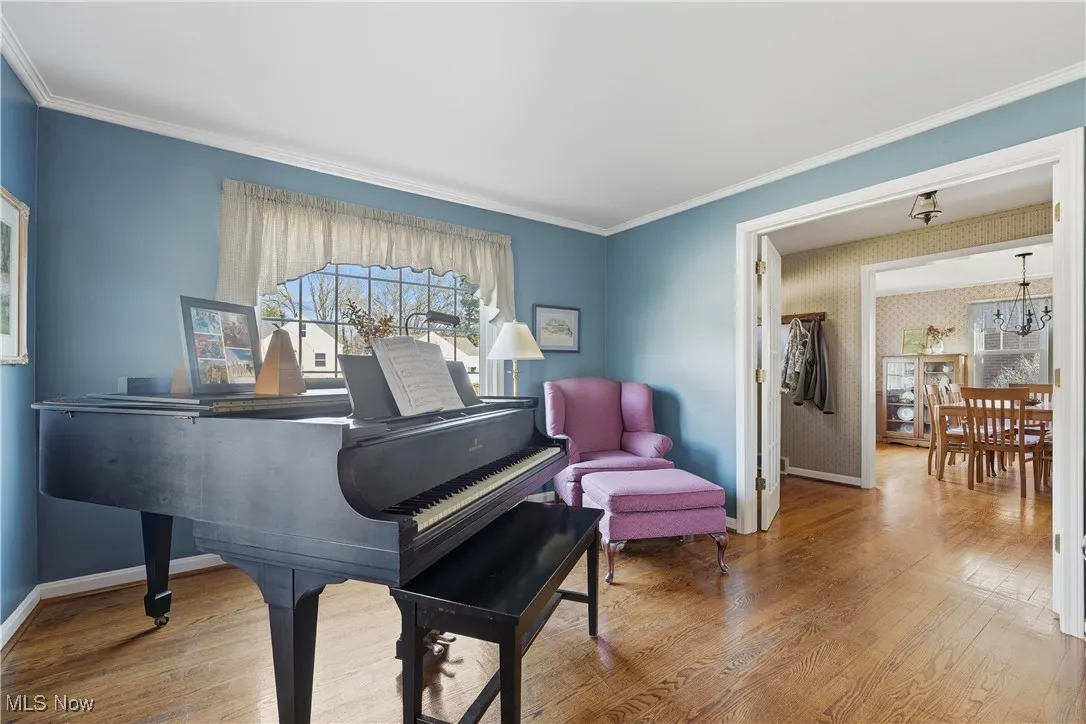 Living area featuring ornamental molding, wood finished floors, and wallpapered walls