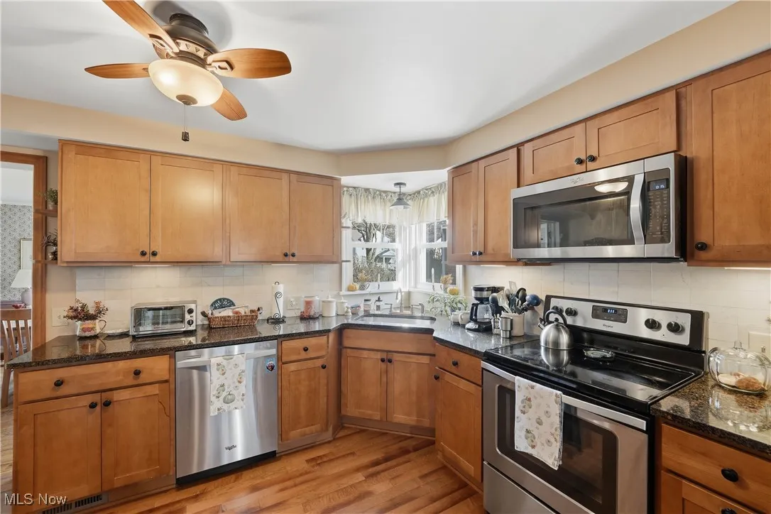 Kitchen with appliances with stainless steel finishes, tasteful backsplash, and brown cabinets