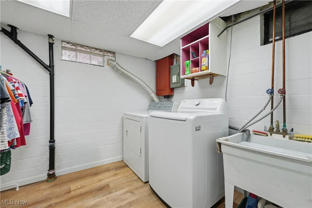 Washroom with light wood-style floors, washer and clothes dryer, electric panel, and a drop ceiling