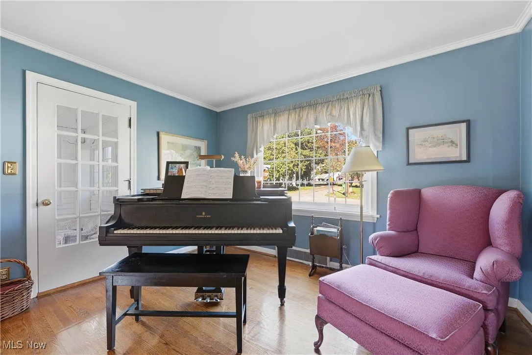 Sitting room with wood finished floors and crown molding