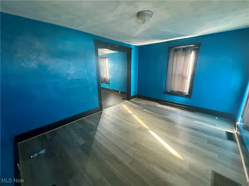Empty room featuring wood finished floors and a baseboard radiator