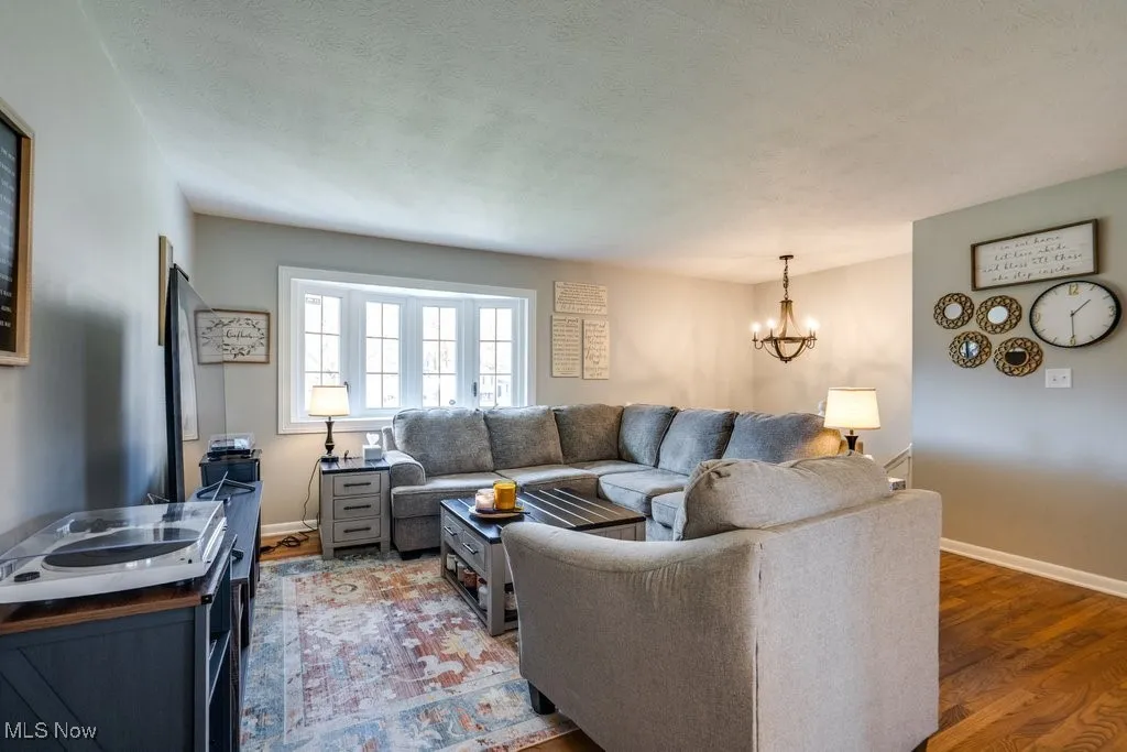Living area featuring a chandelier, wood finished floors, and a textured ceiling