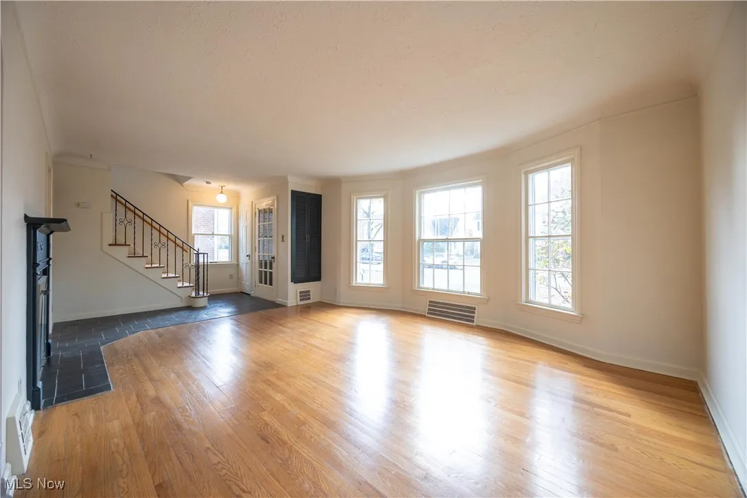Unfurnished living room with stairway, light wood finished floors, and a fireplace