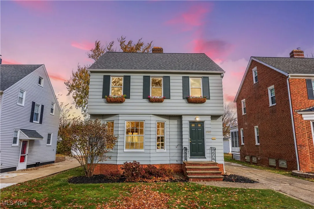 Colonial inspired home featuring a chimney, a shingled roof, and a front yard