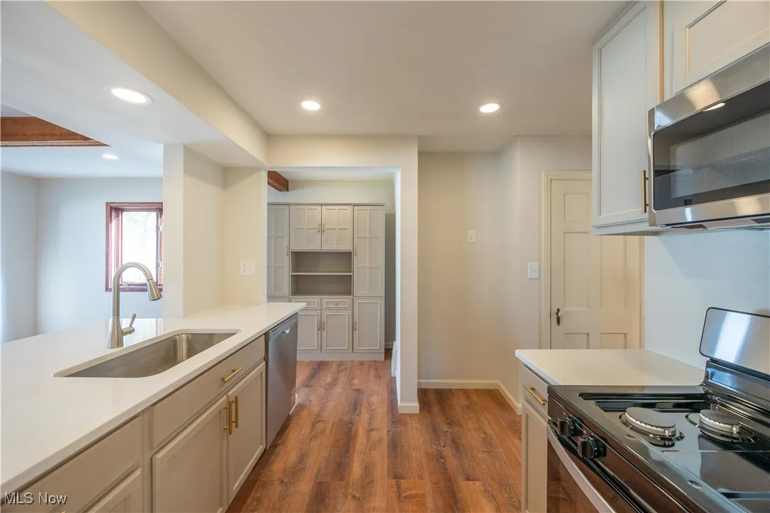 Kitchen featuring stainless steel appliances, recessed lighting, dark wood-style flooring, light stone counters, and white cabinets