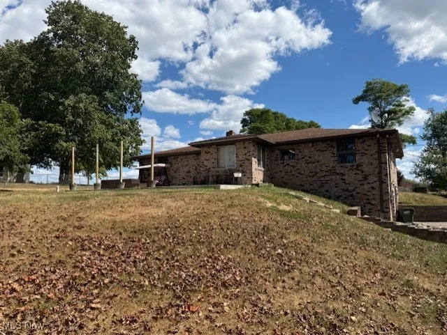 View of side of home with brick siding and a lawn