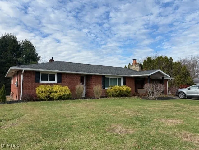 Ranch-style house featuring a front lawn, a chimney, and brick siding