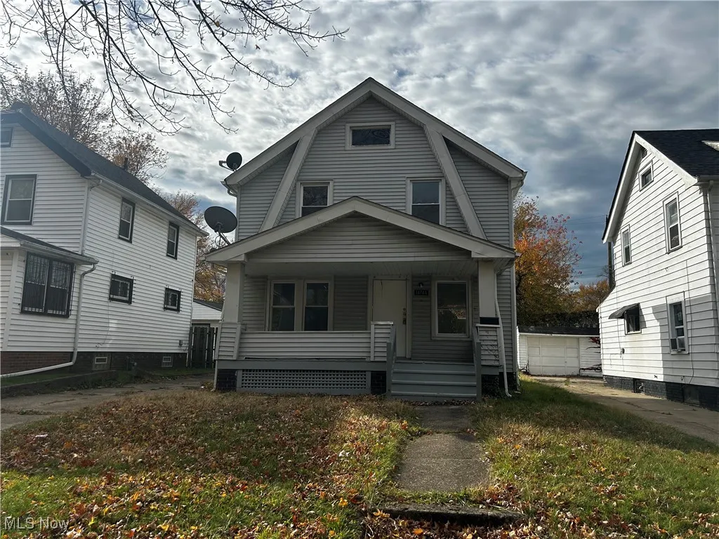 Dutch colonial featuring covered porch, a gambrel roof, and a front lawn