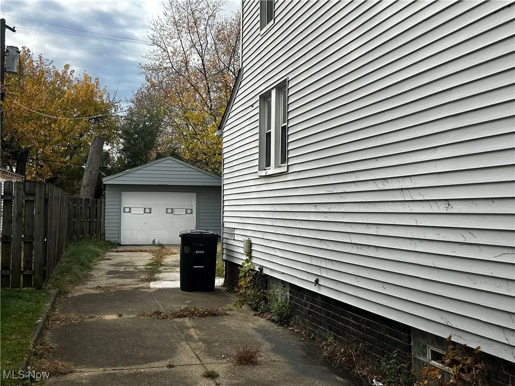 View of property exterior with a detached garage, driveway, and an outdoor structure