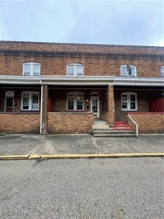 View of front of property with brick siding and covered porch