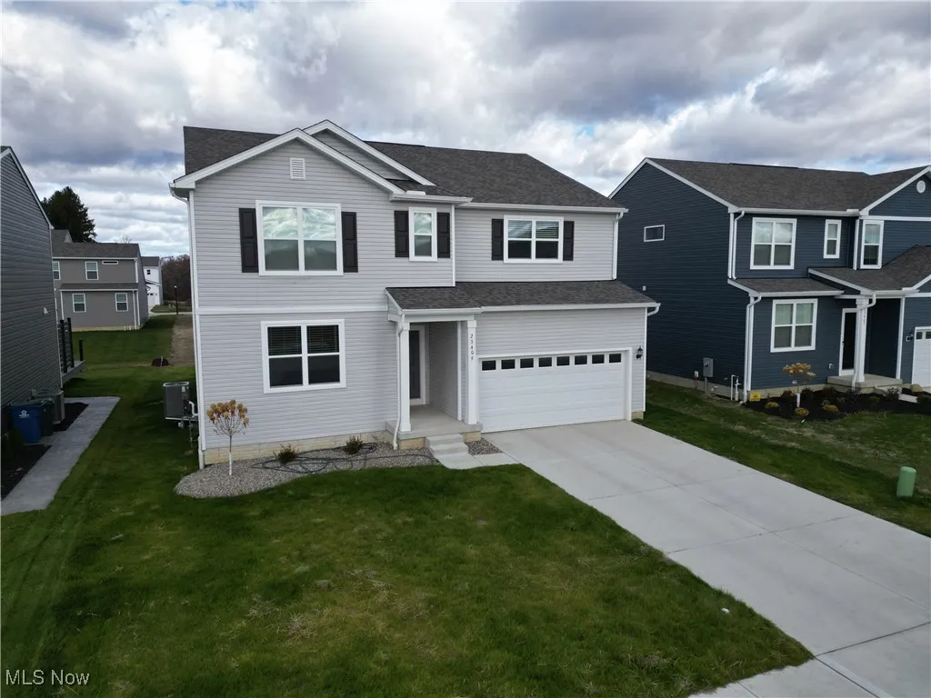 Traditional-style home featuring driveway, a front yard, a garage, and a shingled roof