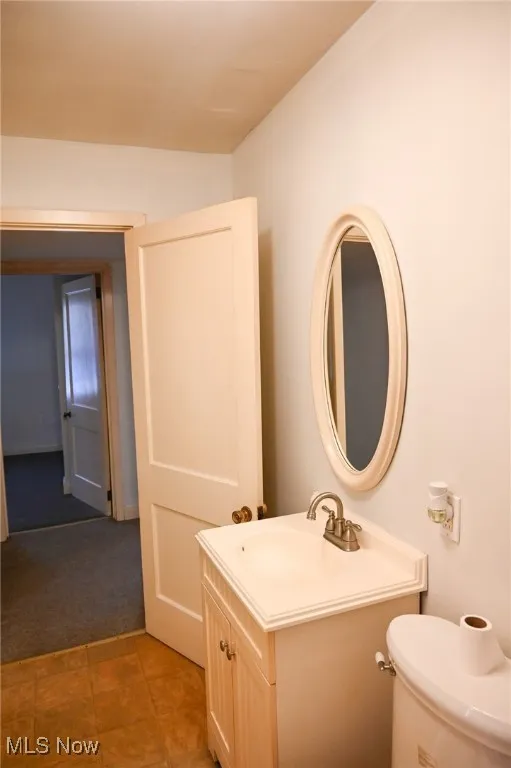 Half bath with vanity, light carpet, and light tile patterned floors
