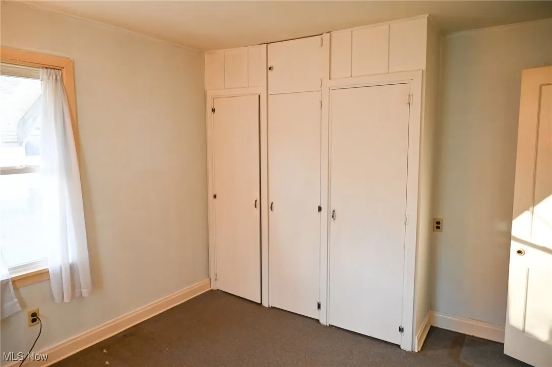 Unfurnished bedroom with a closet and dark colored carpet