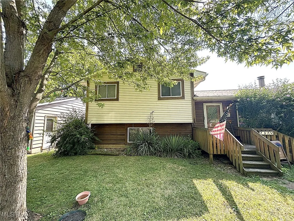 Rear view of house featuring a lawn and a deck