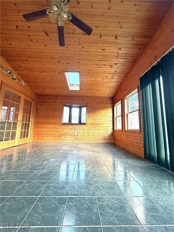 Empty room featuring wooden walls, wooden ceiling, and french doors